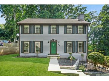 Charming two-story home with a well-manicured front yard, gray siding and dark shutters and a bright green door at 998 Pointer Rdg, Tucker, GA 30084