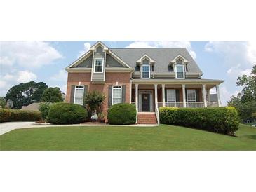 Charming brick two-story home with a welcoming front porch and well-manicured landscaping at 3145 Sweet Basil Ln, Loganville, GA 30052