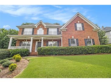 Beautiful brick home with a manicured lawn, lush landscaping, and inviting front porch with classic columns at 5821 Saint Miles Drive Dr, Buford, GA 30518