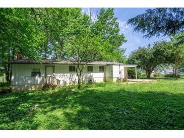 Expansive backyard featuring lush greenery surrounding the charming exterior of this single-story home at 2155 Rosedale Rd, Snellville, GA 30078