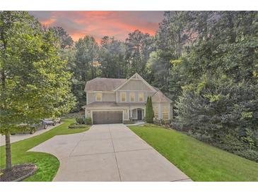 Charming two-story home featuring a manicured lawn and a long driveway under a beautiful sunset sky at 2740 Creekside Manor Dr, Powder Springs, GA 30127