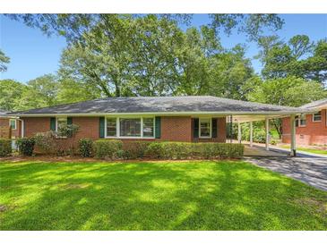 Charming brick home featuring a well-manicured lawn, a covered carport, and lush landscaping creating welcoming curb appeal at 739 Pinehill Se Dr, Smyrna, GA 30080