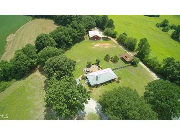 Expansive property featuring a primary home and a secondary structure surrounded by lush greenery and open fields at , Social Circle, GA 30025