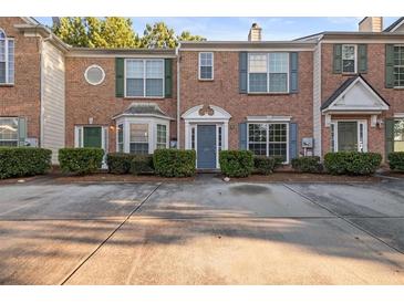 Brick townhome featuring well-maintained landscaping, classic shutters, and assigned parking at 2736 Parkway Trl, Lithonia, GA 30058