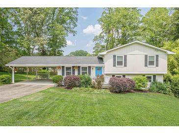 Charming split-level home featuring a manicured lawn, bright blue door, and covered carport, inviting you to call it home at 205 Plantation Sw Rd, Smyrna, GA 30082