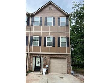Two-story townhouse with brown and tan exterior and a single car garage at 1462 Knights Trl, Stone Mountain, GA 30083