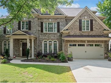 Charming brick home with a two-car garage, beautiful landscaping, and a welcoming front porch at 1450 Liberty Ln, Cumming, GA 30040