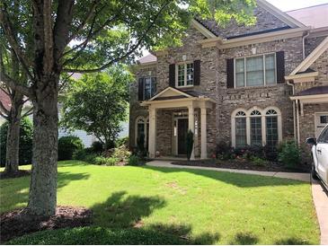 Beautiful brick two-story home featuring a well-manicured front yard with lush green grass and mature shade trees at 1450 Liberty Ln, Cumming, GA 30040