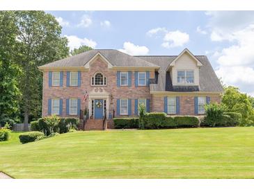 Charming two-story brick home featuring blue shutters and a well-manicured lawn at 3574 Timberloch Trl, Snellville, GA 30039