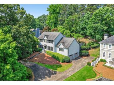 Stately two-story home with a manicured lawn, mature trees, and a circular driveway, offering curb appeal at 3185 Country Club Nw Ct, Kennesaw, GA 30144