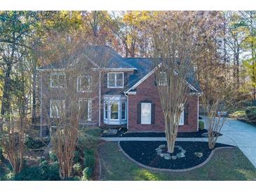 Charming brick two-story home featuring a well-manicured lawn and mature trees at 2001 Towne Lake W Hls, Woodstock, GA 30189