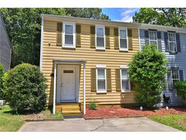 Charming two-story townhouse featuring a classic design with yellow siding and green shutters, surrounded by lush greenery at 4120 Buckley Woods Dr, Norcross, GA 30093