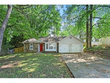 Charming single-story home featuring a stone facade, attached garage, and bright red front door at 971 Clover Ln, Lawrenceville, GA 30044