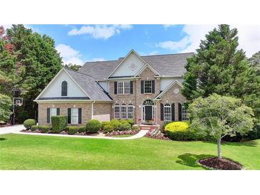 Beautiful two-story brick home with a manicured lawn, lush landscaping, and a classic architectural design at 5357 Harbury Cv, Suwanee, GA 30024
