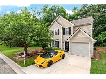 Two-story home featuring a tan exterior, black shutters, manicured lawn and a striking yellow luxury car in the driveway at 248 Springbottom Dr, Lawrenceville, GA 30046