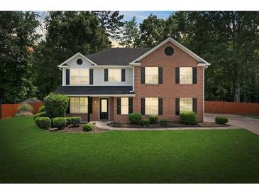 Charming two-story home with brick and siding, surrounded by a lush green lawn and mature trees at 5399 Emily Cir, Ellenwood, GA 30294