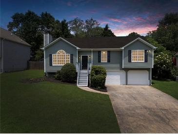 Charming split-level home featuring a manicured lawn, a two-car garage, and inviting curb appeal against a twilight sky at 4255 Brandy Ann Dr, Acworth, GA 30101