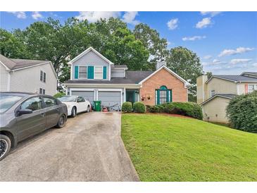 Charming home featuring a landscaped yard, attached two-car garage, and welcoming front entrance at 4945 Penscot Way, Stone Mountain, GA 30088