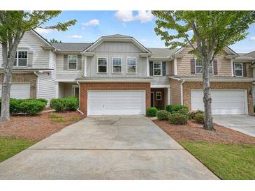 Charming townhome featuring a brick facade, attached garage, and well-maintained landscaping at 411 Mountain View Ln, Woodstock, GA 30188