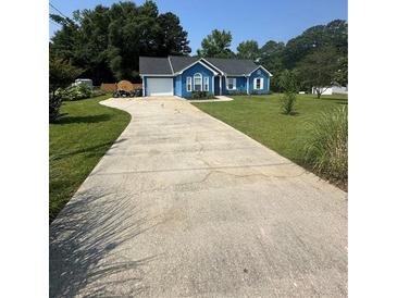 Charming blue home with a long concrete driveway and well-manicured lawn at 160 Springdale Ct, Newborn, GA 30056