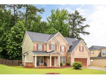 Charming two-story brick home with a well-manicured lawn, inviting front porch, and attached garage at 1110 Cureton Dr, Austell, GA 30106