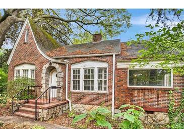 Charming brick home featuring a stone-arched entryway and multiple windows for ample natural light at 1699 Emerald Sw Ave, Atlanta, GA 30310