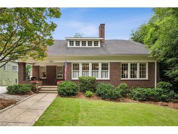 Charming brick home with a well-manicured lawn and an inviting front porch, showcasing classic architectural details at 1371 N Highland Ne Ave, Atlanta, GA 30306
