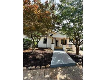 Inviting front yard of a renovated home with mature trees and a modern walkway leading to the entrance at 1766 W Lyle W Ave, College Park, GA 30337