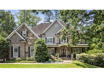 Charming two-story home with a stone and brick facade, lush landscaping, and a covered front porch at 157 Lake Forrest Ne Ln, Atlanta, GA 30342