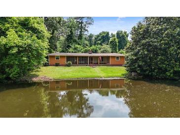 Charming ranch-style home reflected in a peaceful pond surrounded by lush greenery and mature trees at 347 Oakhurst Dr, Marietta, GA 30066