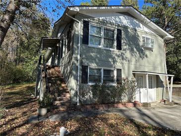 Charming two-story home featuring brick siding, black shutters, and mature trees in a serene neighborhood setting at 915 Lake Dr, Snellville, GA 30039