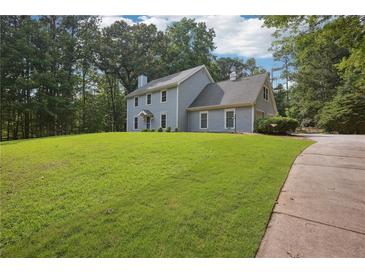 Traditional two-story home featuring a lush front yard, mature trees, and a charming covered entryway at 285 Aspen Way, Fayetteville, GA 30214