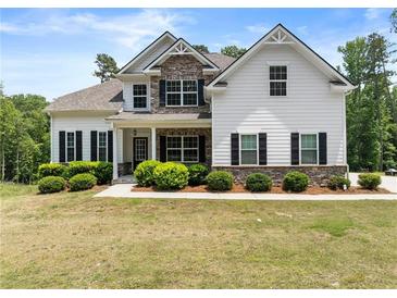 Beautiful home featuring stone accents, a covered porch, lush landscaping, and a well-manicured lawn at 2855 Pilgrim Mill, Cumming, GA 30041