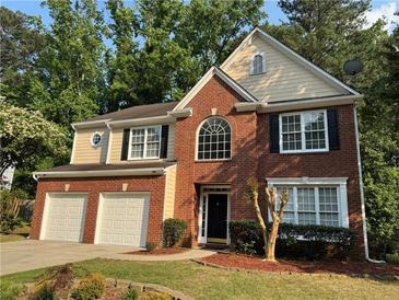 Charming brick and siding two-story home with well-manicured lawn, landscaping, and a two-car garage at 1415 Stoney Field Pl, Lawrenceville, GA 30043