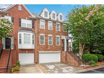 Charming brick townhome featuring an attached garage, classic architectural details, and a well-manicured front yard at 451 Tioram Se Ln, Smyrna, GA 30082