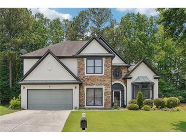 Charming home with a stone and stucco facade, complemented by a well-manicured lawn and lush landscaping at 9811 Spyglass Dr, Villa Rica, GA 30180