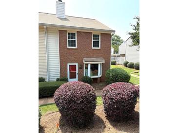 Charming brick two-story townhome featuring a bay window and neatly manicured shrubbery in the front yard at 210 Mill Creek Pl, Roswell, GA 30076