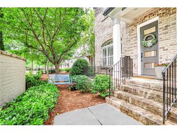 Charming brick home entrance featuring landscaped garden, a blue bench and a decorative front door at 4202 Deming Cir, Sandy Springs, GA 30342