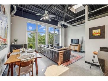 Bright living room with large windows, open ceiling, and a dining area, creating a spacious loft-style apartment at 5200 Peachtree Rd # 3420, Atlanta, GA 30341