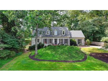Charming single-story home with beautiful landscaping, featuring a classic brick facade and mature trees at 5285 Bannergate Dr, Johns Creek, GA 30022