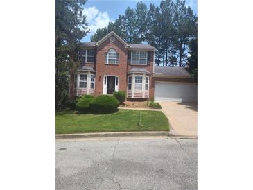 Charming two-story red brick home featuring a well-manicured lawn and attached garage at 1138 School Side Dr, Lithonia, GA 30058