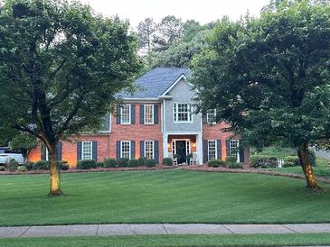 Charming brick home with manicured lawn and inviting front porch featuring rocking chairs at 3532 W Hampton Nw Dr, Marietta, GA 30064