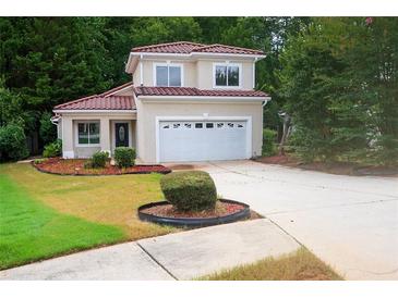 Charming two-story home boasts a lush front lawn, manicured shrubbery, and a convenient two-car garage at 128 Garden Walk, Stockbridge, GA 30281