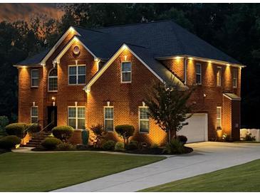 Stately brick home with manicured lawn, lit dramatically with landscape and architectural lighting at 2725 Bailey Ne Pl, Conyers, GA 30013