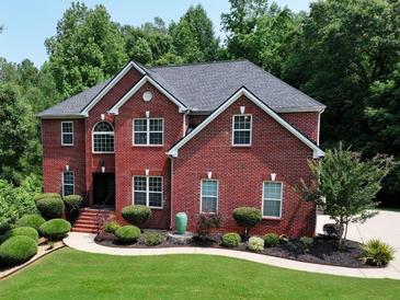 Beautiful red brick home with lush landscaping, a well-manicured lawn and a walkway to the front door at 2725 Bailey Ne Pl, Conyers, GA 30013