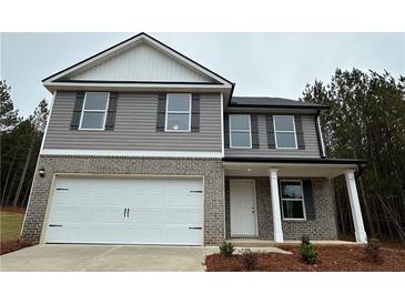 Two-story home features a two-car garage, a covered porch, and a yard surrounded by mature trees at 123 Deer Xing, Temple, GA 30179