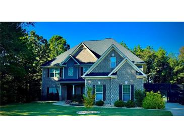 Beautiful two-story brick home with lush lawn, mature trees and inviting covered front porch at 704 Kenton Ct, Locust Grove, GA 30248
