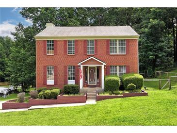 Charming brick home featuring red shutters, a well-manicured lawn and beautiful landscaping at 2621 Garland Way, Duluth, GA 30096
