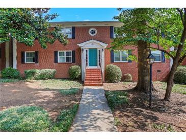 Charming brick home featuring a well-manicured lawn, colorful teal door and a welcoming facade at 4282 Roswell Ne Rd # K3, Atlanta, GA 30342
