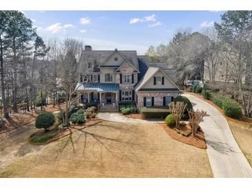 Stately two-story brick home with a covered porch, manicured landscaping, and a long driveway at 9035 Brixham Ct, Suwanee, GA 30024